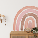 A close-up of an Autumn Rainbow wall decal in a nursery. The gentle hues of pinks and browns add a whimsical, natural vibe to the room, perfectly paired with a wooden cabinet and decor elements.