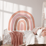 A cozy girls' bedroom with an Autumn Rainbow wall decal above the bed. The room features a soft pink blanket, white metal bed frame, and a dreamy canopy, creating a warm and inviting space.