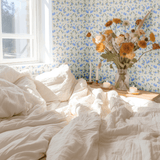 Cozy bedroom with Blueberry Fields floral wallpaper as a feature wall, adding a touch of nature-inspired decor with shades of blue and green