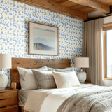 Modern rustic bedroom styled with Blueberry Fields wallpaper, showcasing blue botanical prints against a cozy wood-accented room