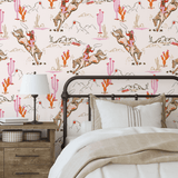 Cozy bedroom with a single bed against a Coral Rodeo wallpaper accent wall, designed with cowgirl and desert motifs in pink and coral hues