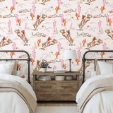 Western-themed girls' bedroom decorated with Coral Rodeo wallpaper as an accent wall, showcasing cowgirl illustrations with desert landscapes and cactus details