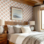 A cozy bedroom with a warm wooden bed frame and floral damask wallpaper featuring soft orange blooms