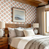 A cozy bedroom with a warm wooden bed frame and floral damask wallpaper featuring soft orange blooms