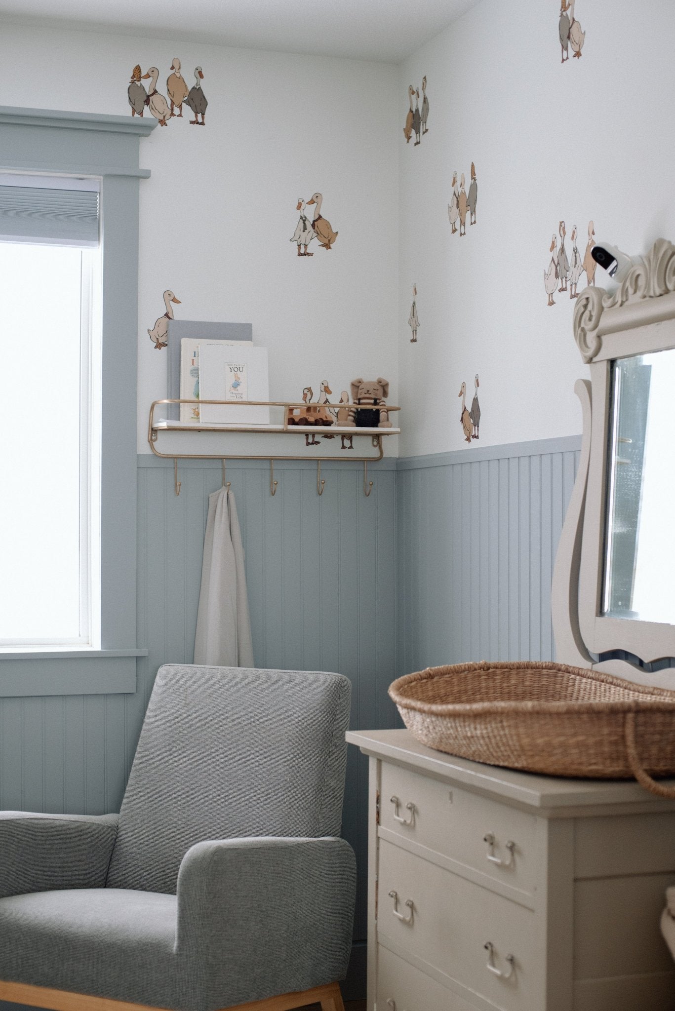 Beautiful nursery with blue wainscotting, and duck/geese decals placed above on white wall.