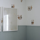 Beautiful nursery with blue wainscotting, and duck/geese decals placed above on white wall.
