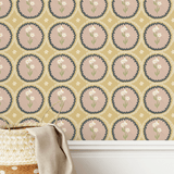 A basket with a beige linen cloth in front of a mustard yellow scalloped wallpaper with dusty pink floral medallion designs, creating a cozy and rustic aesthetic.