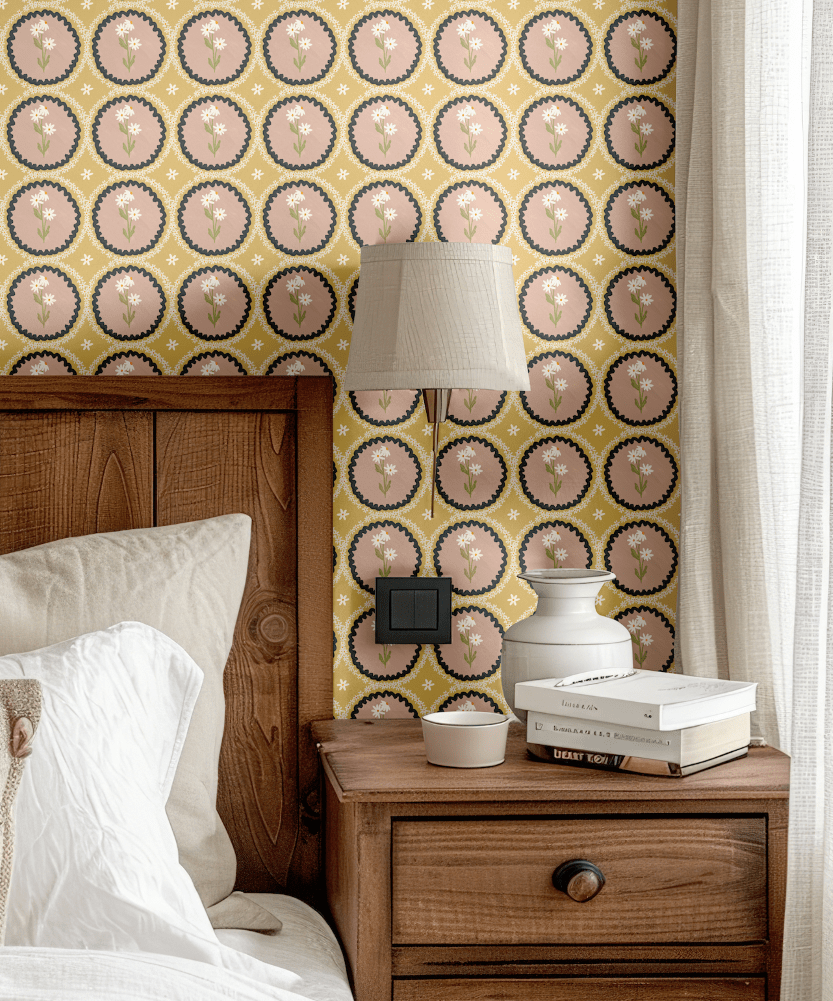 A wooden bedside table with neutral bedding styled against mustard yellow floral scalloped wallpaper, enhancing a rustic bedroom vibe.