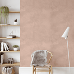 Accent wall with dusty rose pink limewash wallpaper, paired with modern wooden shelves and a cozy chair in a calm reading nook