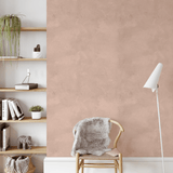 Accent wall with dusty rose pink limewash wallpaper, paired with modern wooden shelves and a cozy chair in a calm reading nook