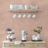 Earthy pink limewash wallpaper used in a coffee bar setting with rustic farmhouse decor and natural wooden shelves