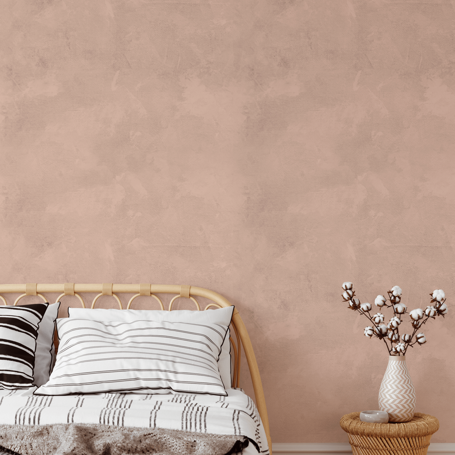 Earthy pink limewash wallpaper in a boho-inspired bedroom with woven furniture and neutral bedding for a soft, calming ambiance