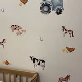 Close-up of a nursery wall decorated with farm animal decals, including a tractor, horses, cows, and chickens. A wooden toddler bed is partially visible, adding to the room's rustic charm