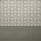 A room with a wooden floor and a light grey-green wallpaper featuring a neutral lotus flower pattern. The bottom portion of the wall has dark grey-green wainscoting with decorative molding, creating a classic and elegant look.