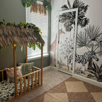 Jungle safari playroom decor with a safari mural showcasing giraffes, zebras, and tropical plants. Wooden crib under a thatched canopy adorned with greenery, creating a tropical, adventurous feel.