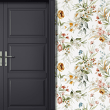 A stylish black door contrasting against a wall with vibrant watercolor floral wallpaper, creating a chic entryway.
