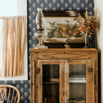 Vintage kitchen corner with navy blue floral wallpaper, an antique wooden cabinet, and decorative rustic elements