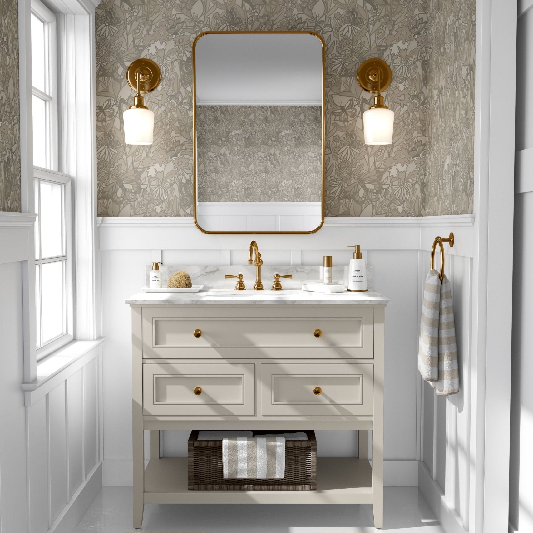 A stylish bathroom with walls covered in a neutral-toned butterfly and floral wallpaper. The decor includes a white vanity with gold handles, a white marble top, and brass fixtures.
