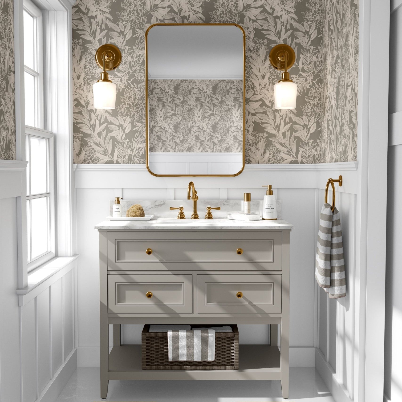  A well-lit bathroom interior with walls covered in a cream leaf pattern wallpaper that matches the previous image, completed with a wooden vanity with gold accents and a rectangular mirror.