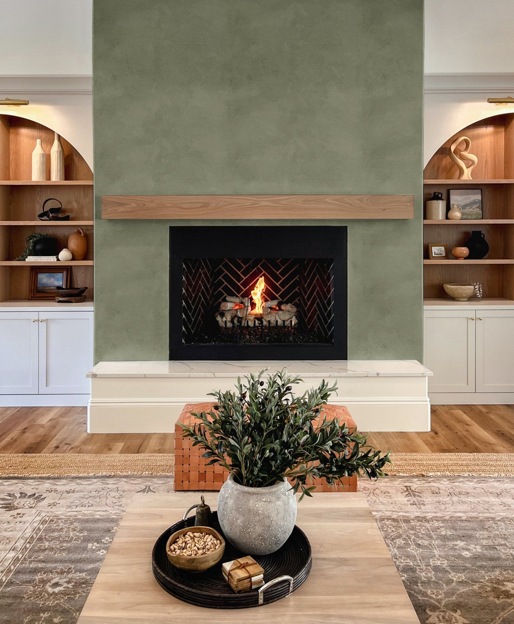 Wallpaper on fireplace feature wall with built-in shelving – olive green wallpaper fireplace, modern rustic wall decor, green limewash mural