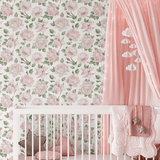 A cozy nursery room with a white crib adorned with a pink star pillow and a heart-shaped pillow, set against a wall covered in pink rose-patterned wallpaper. A pink canopy with cloud-shaped decorations hangs over the crib, adding a dreamy touch to the room.