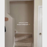 Brown striped wallpaper in stairwell with wedding photos framed on wall.