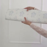 Unrolling beautiful white wallpaper with duck egg blue vintage floral print. 