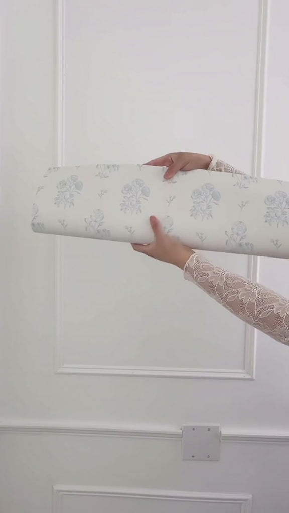 Unrolling beautiful white wallpaper with duck egg blue vintage floral print. 