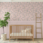 Rose floral wallpaper in gender-neutral nursery with wooden crib, blush paneling, and fiddle leaf fig plant for natural decor