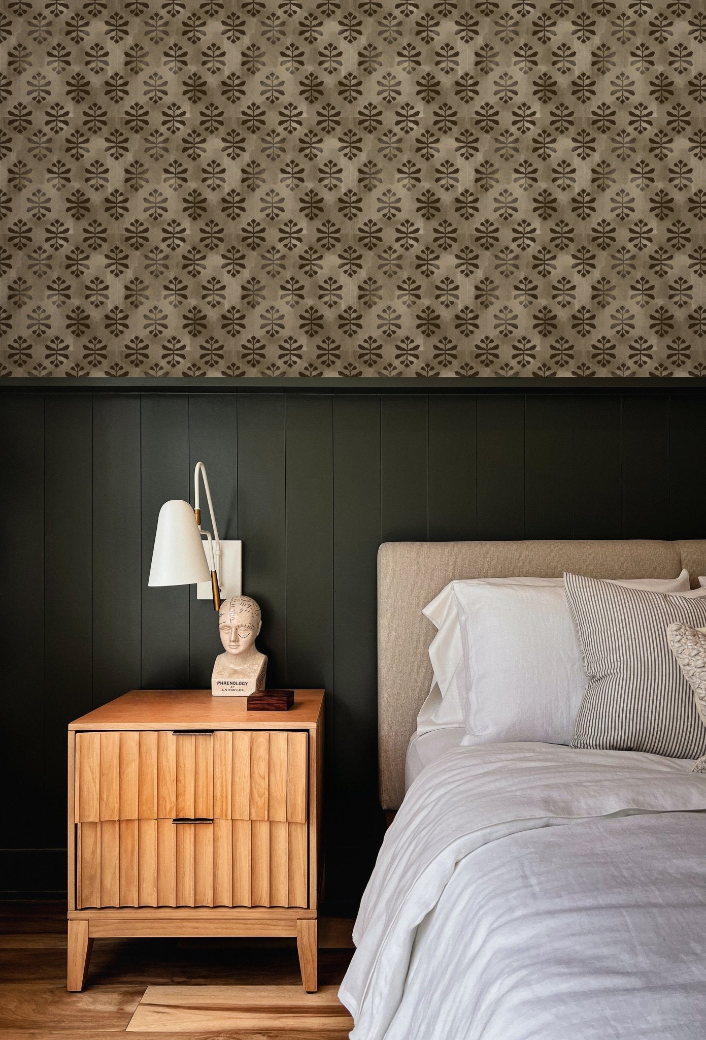 wallpaper above green wall treatment in bedroom with bed and side table