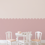 Soft dusty pink scallop wall panels in a playroom with white furniture.