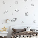 Kids bed with brown polka dot bedding under a wall filled with planets and stars decals.