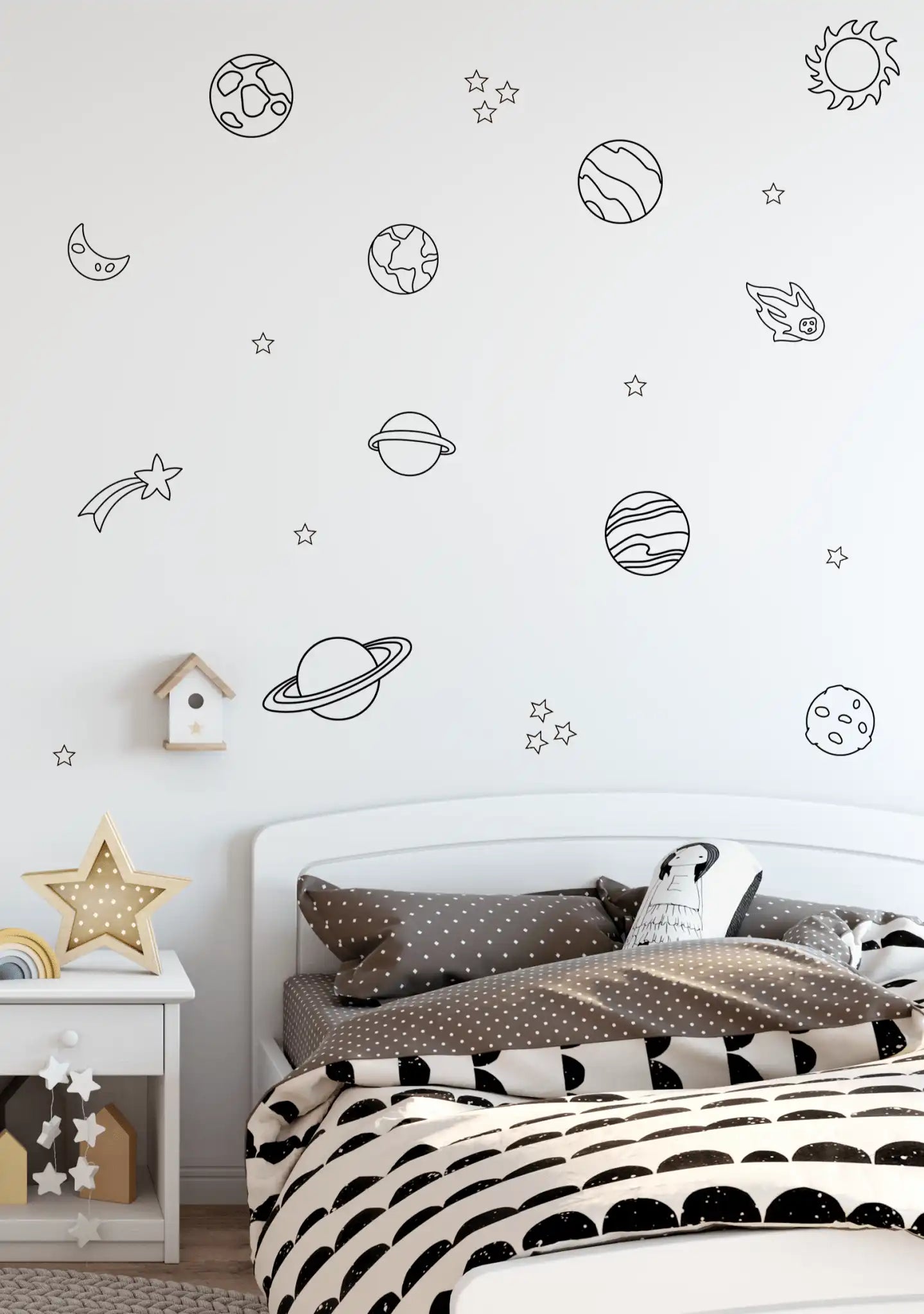 Kids bed with brown polka dot bedding under a wall filled with planets and stars decals.