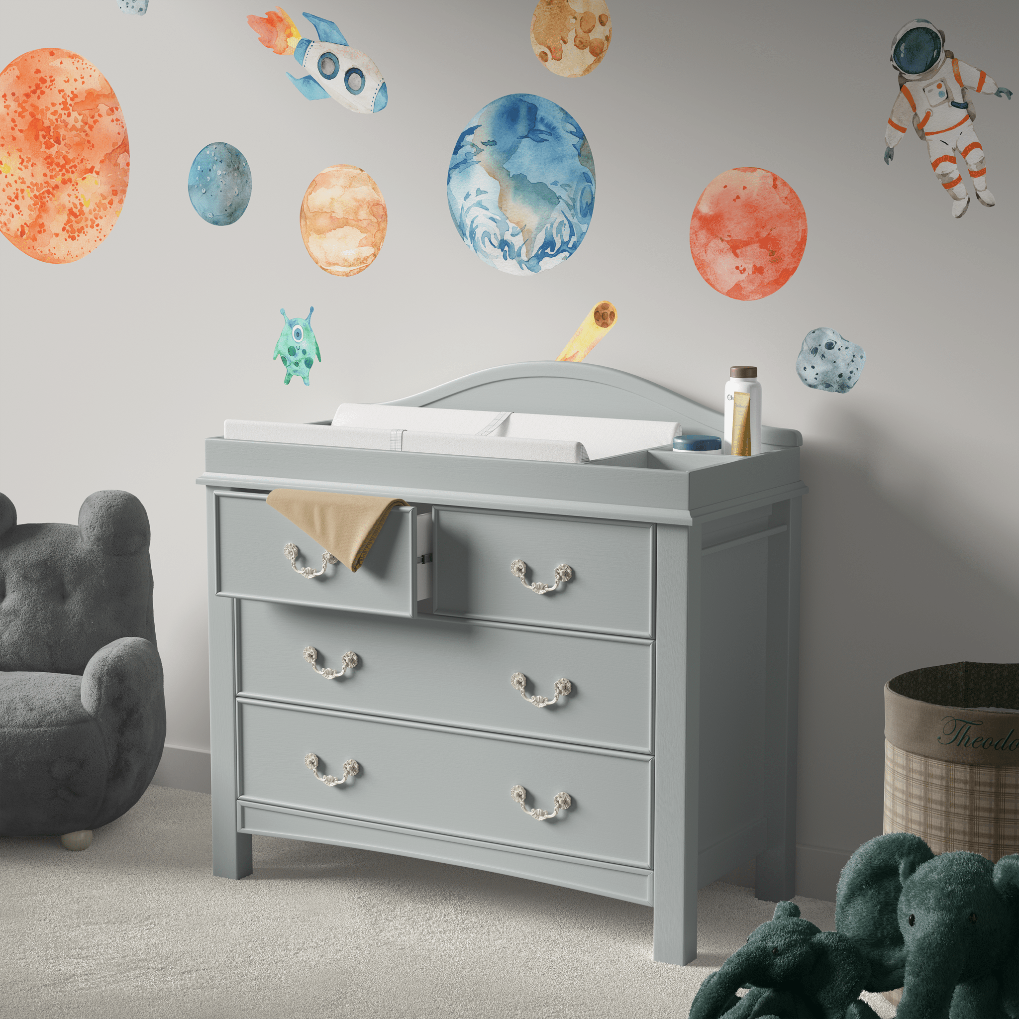 Changing table area decorated with space decals, featuring planets, a rocket, and an astronaut, creating a fun and imaginative space for a nursery