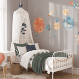 Cozy bedroom with space-themed wall decals, showcasing watercolor planets, rockets, and an astronaut for a whimsical space adventure theme