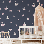 Swan and bow wall decals on a navy blue wall in a girly nursery with a white crib and pink canopy.