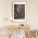 A stylish console table against a wall decorated with swan wallpaper, featuring a framed art piece, a modern lamp, and decorative items, along with a cozy stool and a vase of dried flowers