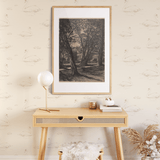 A stylish console table against a wall decorated with swan wallpaper, featuring a framed art piece, a modern lamp, and decorative items, along with a cozy stool and a vase of dried flowers