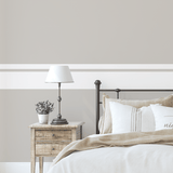 Cozy bedroom scene with beige walls and customizable thick and thin stripe wall decals above the headboard.