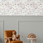 Children's playroom featuring the Vintage Anemones peel and stick wallpaper above a grey wainscoting, paired with a cozy armchair, wooden toys, and a plush toy, creating a warm and inviting environment