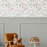 Children's playroom featuring the Vintage Anemones peel and stick wallpaper above a grey wainscoting, paired with a cozy armchair, wooden toys, and a plush toy, creating a warm and inviting environment