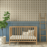 Nursery decorated with Vintage Aster Wallpaper, small floral design paired with wooden crib and blue wainscoting