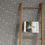 Rustic wooden ladder leaning against a wall covered in our Winter floral peel and stick wallpaper, highlighting the traditional design with subtle earth-toned flowers and leaves on a grey backdrop