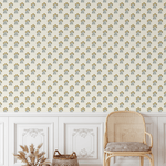 Vintage yellow floral block print wallpaper in a rustic living room with white wainscoting and a rattan chair.