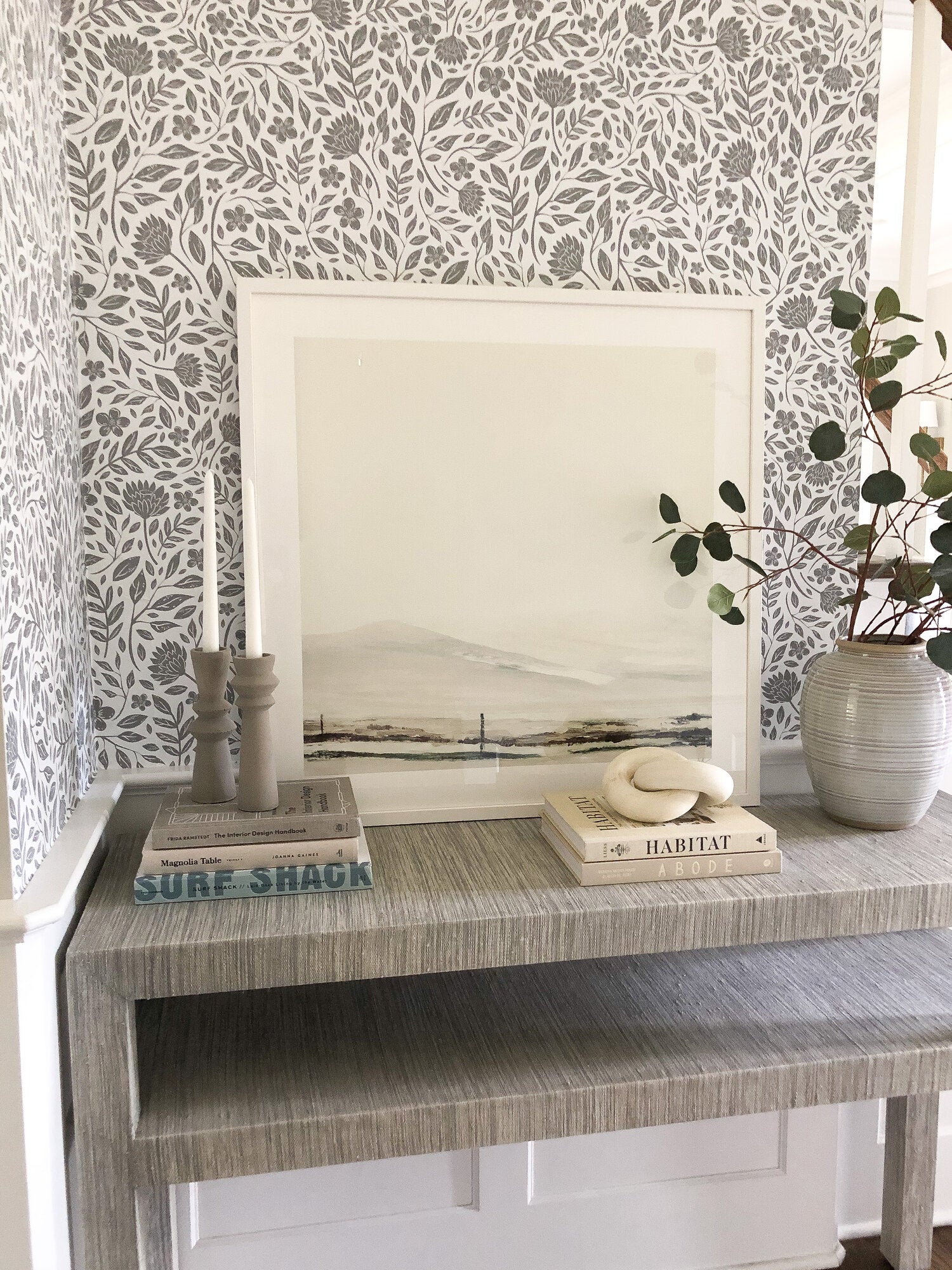Table decor with books and decorated with grey and white peel and stick floral wallpaper
