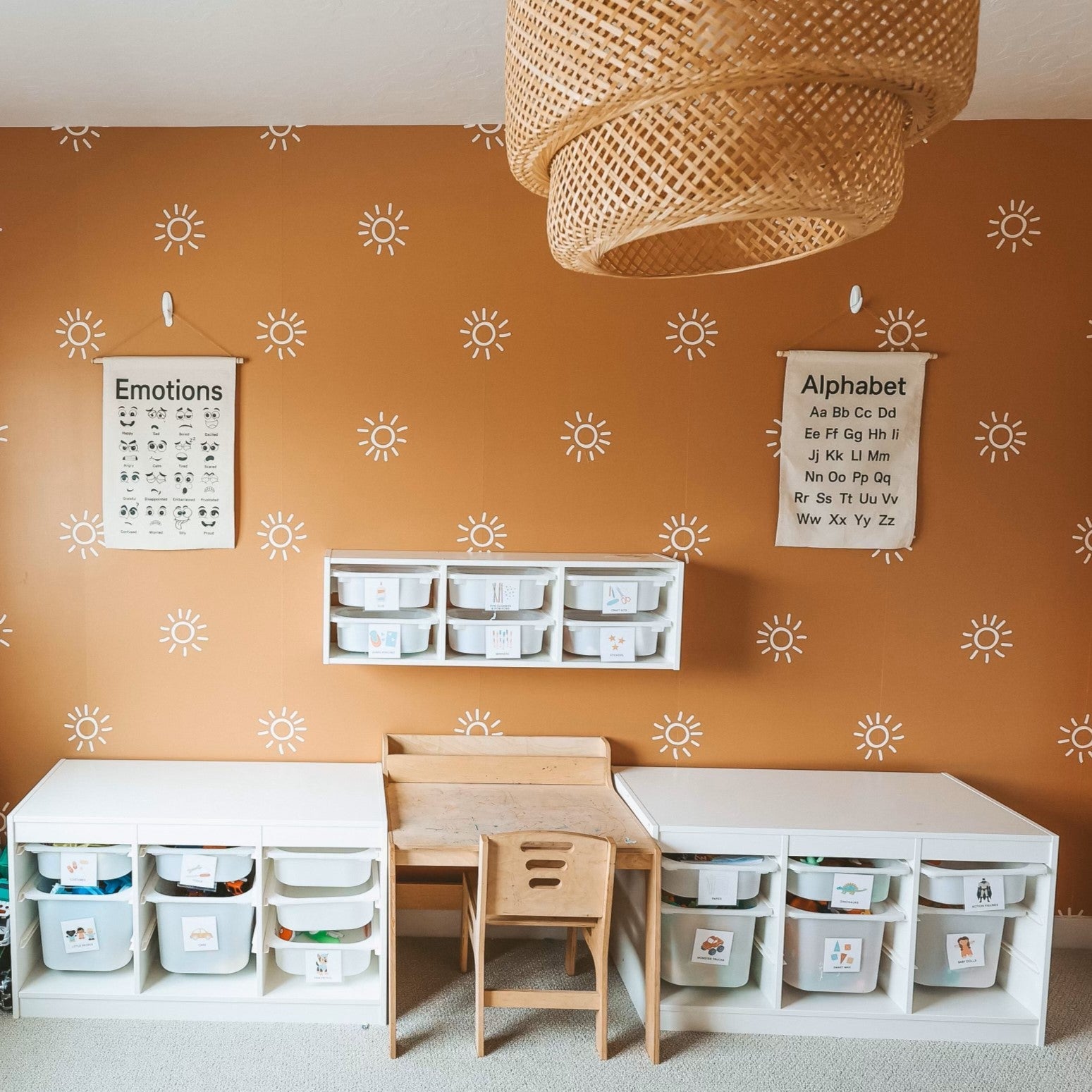 Children's learning space with terracotta walls adorned with sunburst decals, educational posters, and organized storage bins