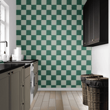 Spacious kitchen interior with checkerboard green and white wallpaper, black countertops, white cabinets, and woven laundry baskets