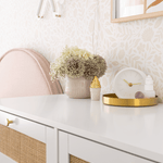 Flower wallpaper behind a white dresser with gold accents