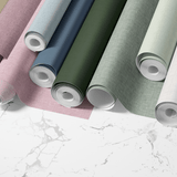 Faux grasscloth wallpaper rolls, featuring a variety of colors including brown, purple, cream, pink, light blue, navy, forest green, sage green and charcoal