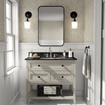  A bathroom with beige floral wallpaper, white vanity with black countertop, rectangular mirror, and black sconce lights.